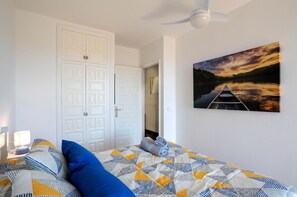 A bedroom with a bed, pillows, a painting of a sunset, and a white wardrobe. - Bonita Casa CON Jardin Privado Y Piscina Comunitaria (Palafrugell)