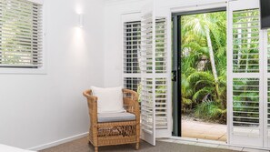 Relax in a serene space with a wicker chair and a view of the lush garden through the glass door.