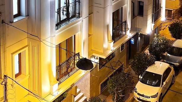 Un hôtel à plusieurs étages, doté de balcons, d’un parking et d’une façade bien éclairée.