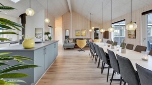 Cozinha moderna com ilha central, piso de madeira e iluminação pendente.