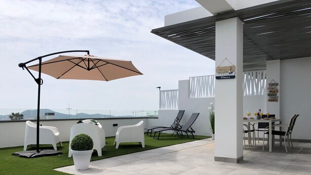 A modern outdoor patio with a dining area, chairs, and a table.
