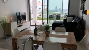 A modern living room with a dining area, a TV, and a view of the cityscape.