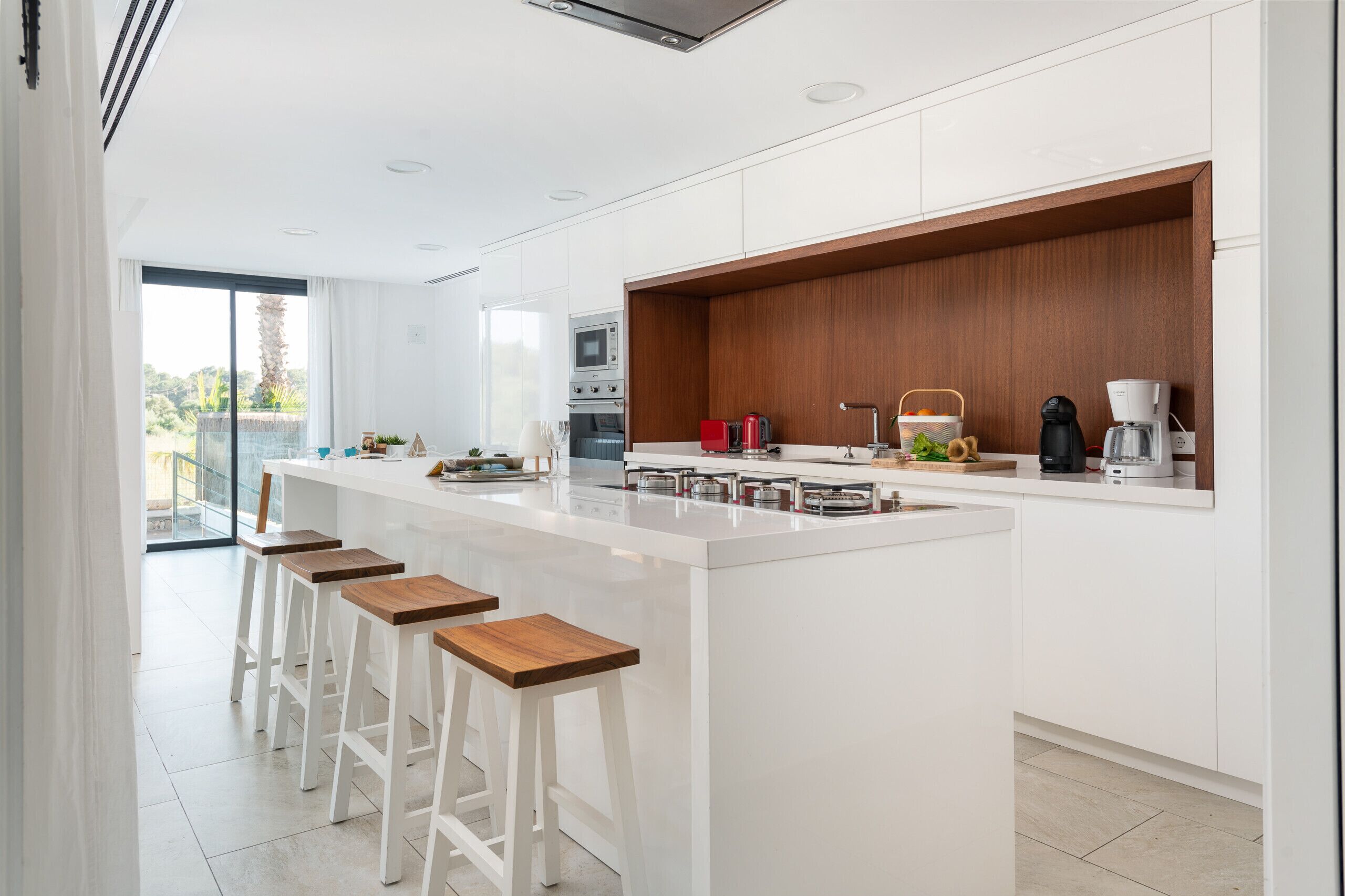 A modern kitchen with a large island, white cabinetry, and wooden accents.