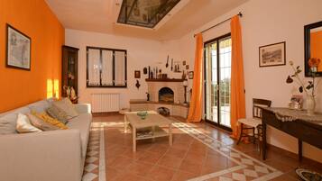 Uma sala de estar com sofá, mesa de centro, lareira e área de jantar com mesa e cadeiras.