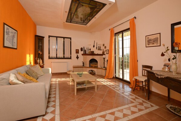 A living room with a sofa, a coffee table, a fireplace, and a dining area with a table and chairs. - Villa Torres (Scicli)