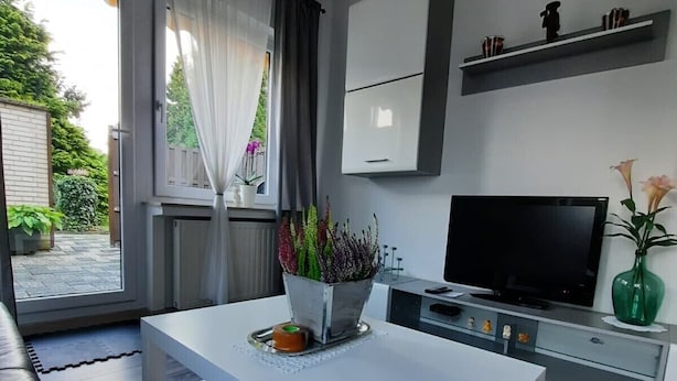 Une cuisine moderne avec un plan de travail blanc, un four encastré et un téléviseur à écran plat.
