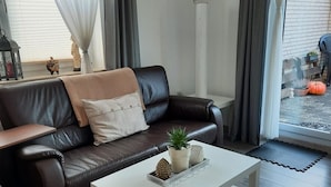 Un salon moderne avec un canapé en cuir marron foncé, une table basse blanche et une petite plante en pot.