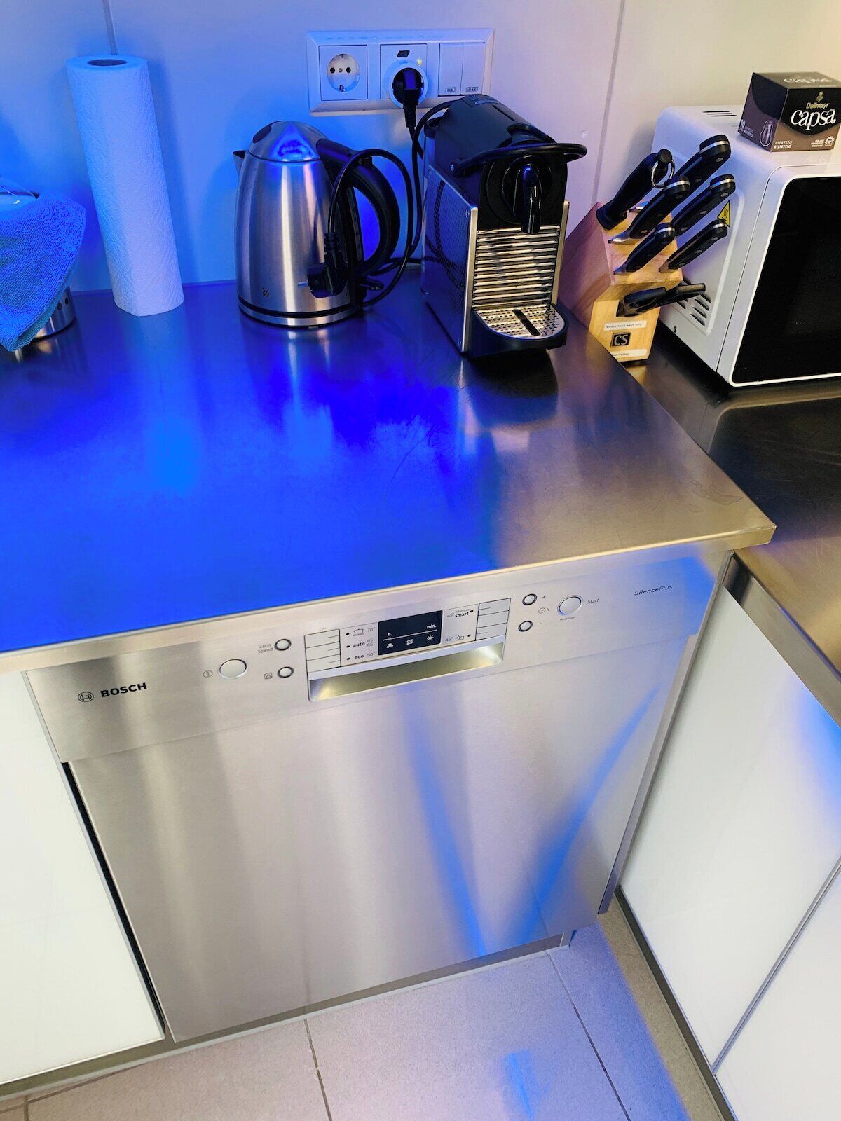 A kitchen with a Bosch dishwasher, a kettle, a coffee maker, and a box of Cassa espresso capsules.