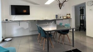 Una cocina moderna con un televisor de pantalla plana, una decoración de cornamenta de ciervo, una cafetera y un reloj en la pared.