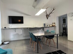 A modern kitchen with a flat-screen TV, a deer antler decoration, a coffee machine, and a clock on the wall.