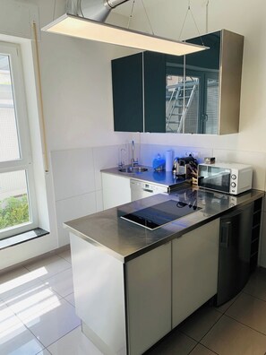A modern kitchen with a central island, a dishwasher, a microwave, and a sink.