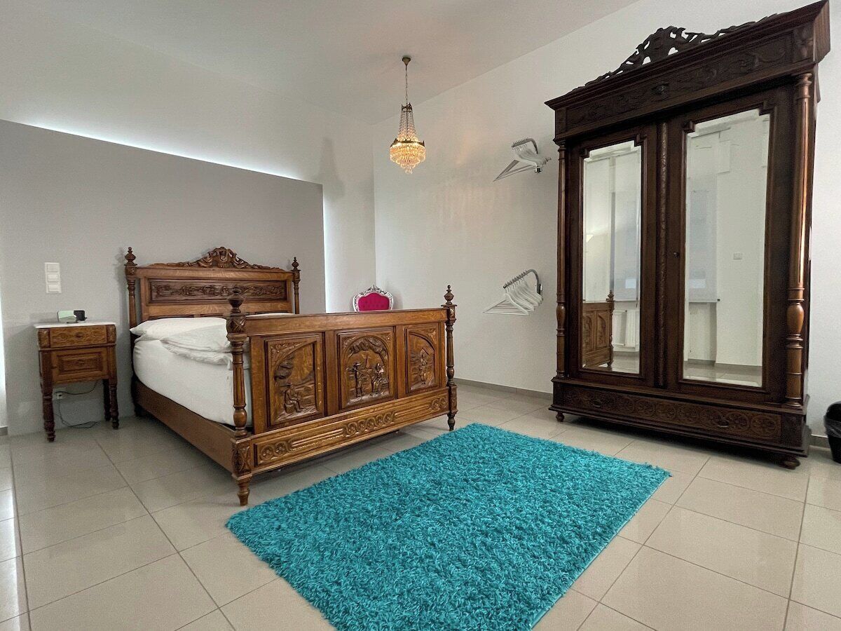 Un dormitorio con una cama de madera, una mesita de noche, un armario grande y una araña.