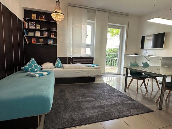 A modern bedroom with a bed, bedside tables, a desk, and a TV.