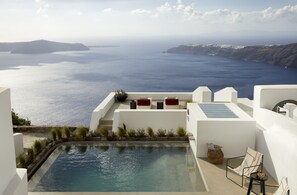 Zona de piscina con vistas al mar, paredes blancas y algunas áreas de descanso.