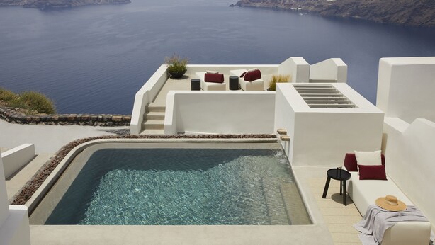 A rooftop pool with a view of the sea, white walls, and red and white furniture. - Atoles Retreat (Santorini)