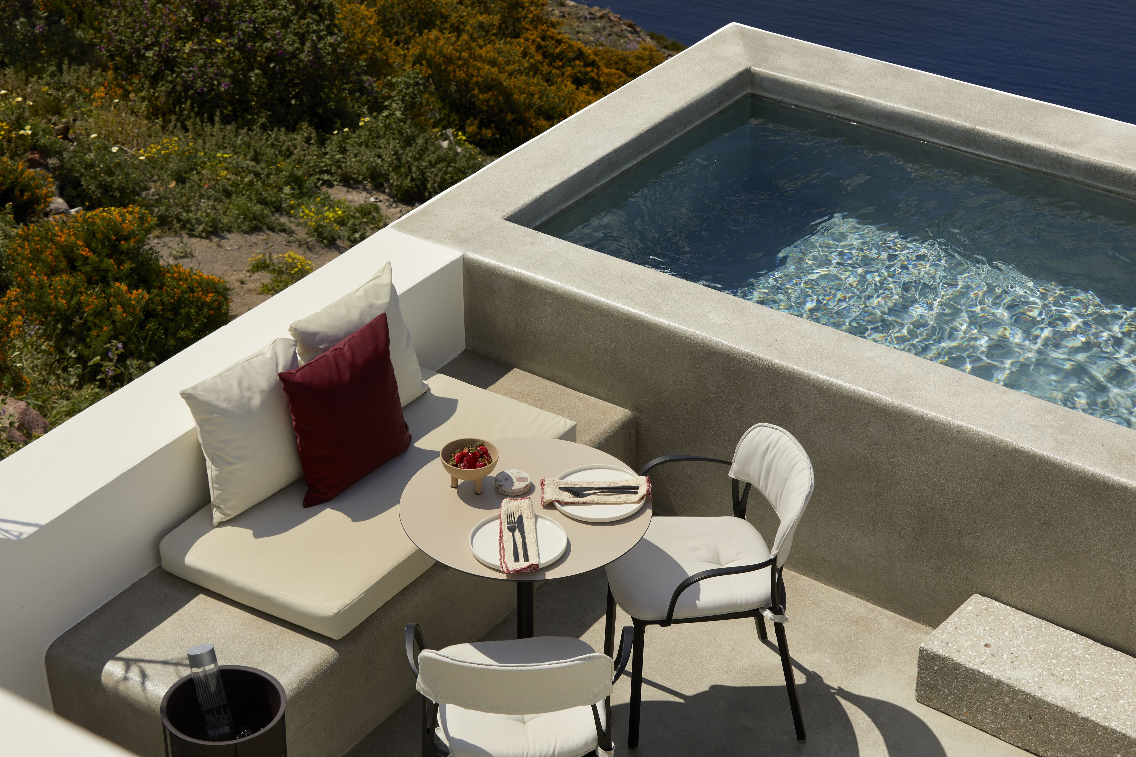 A modern outdoor seating area with a pool, including a sofa, chairs, and a dining setup.