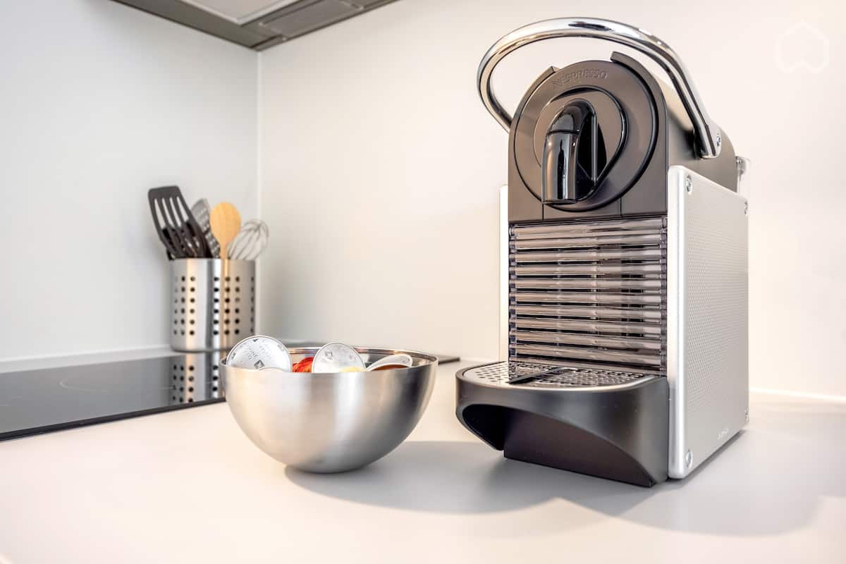 A kitchen with a coffee machine, a bowl, and a utensil holder.