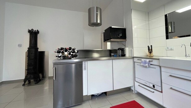 Een moderne keuken met witte kasten, roestvrijstalen apparatuur en een rood vloerkleed.