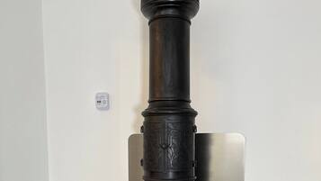 Un alto e decorato fornello con motivi intricati, posizionato su un pavimento piastrellato davanti a una parete semplice.