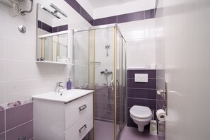 Ein modernes Badezimmer mit einer Duschkabine aus Glas, einem weißen Waschbecken und einer Toilette.