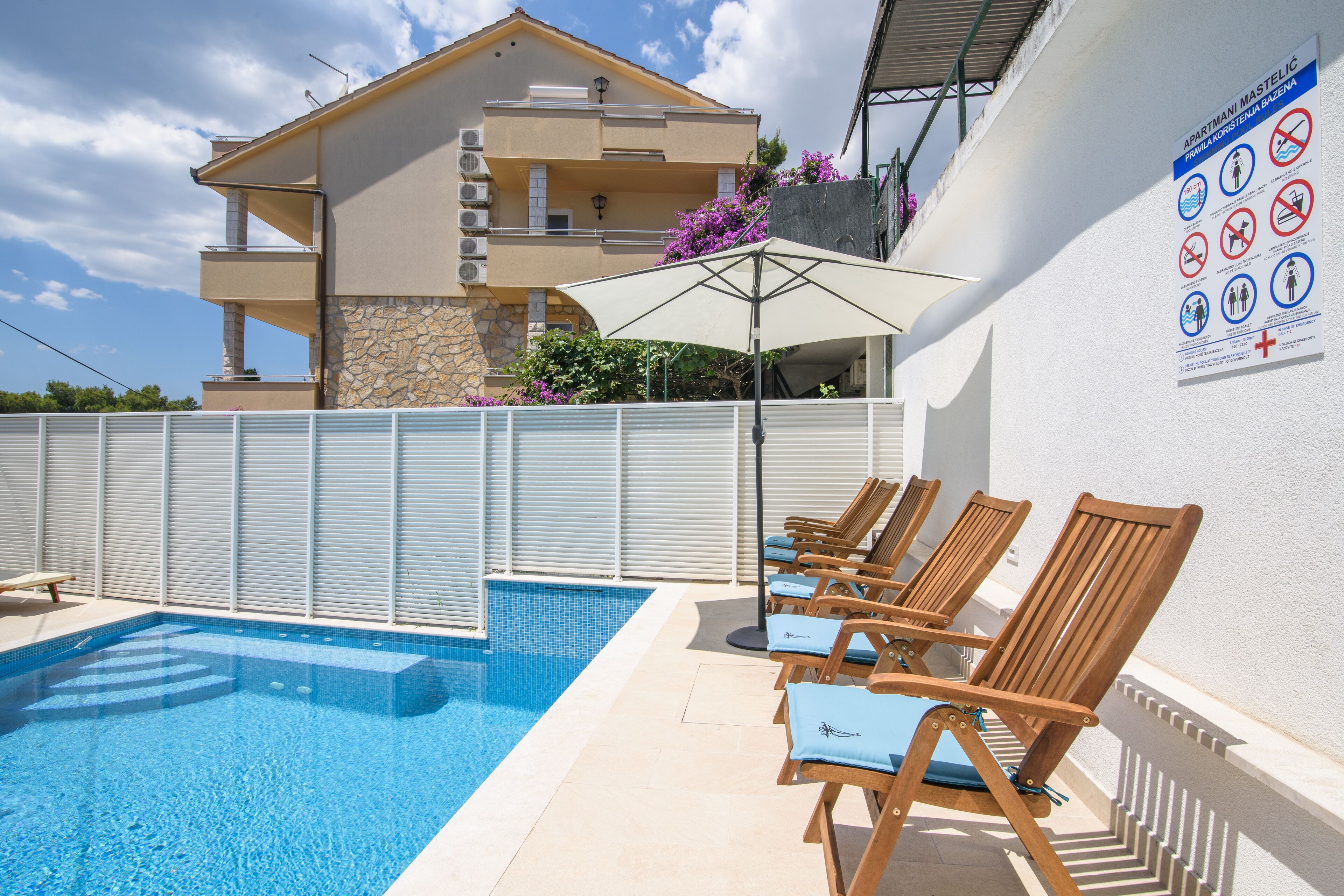 A swimming pool with lounge chairs and a building with balconies in the background.
