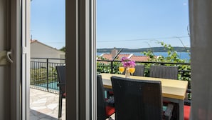 A terrace with a table and chairs, a view of the sea, and a pool in the background. - A3 90m2 apt W.shared Pool & Balcony,next to Beach (Trogir)