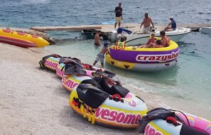 Auf dem Strand liegen Luftmatratzen, umgeben von Menschen.