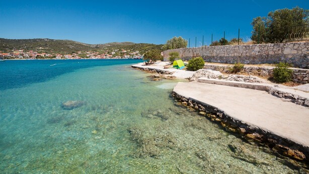 A coastal area with clear blue water, a stone wall, and a small green tent. - 2 - Modern Apartment With Garden, 80m From Beach (Marina)