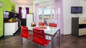 A modern kitchen with a dining area, a TV, and a balcony with a view. - 1 - Modern apt w big Garden & Terrace w. sea View (Marina)
