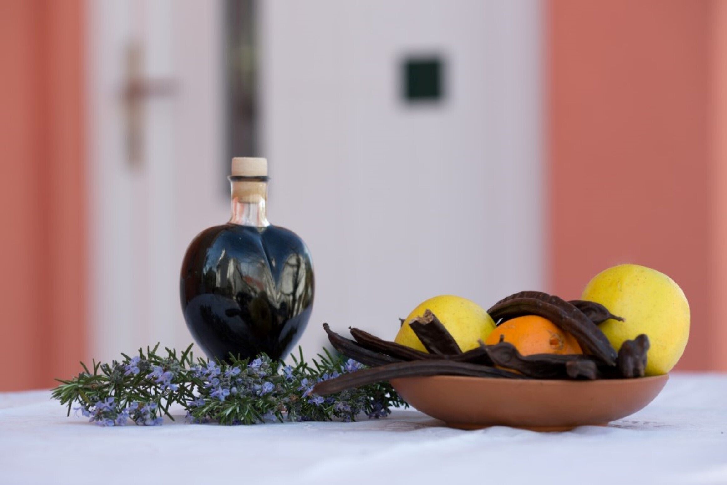 A table with a bowl of fruit and a bottle.