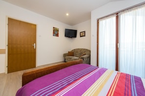 Une chambre à coucher avec un lit, une chaise, un téléviseur et une porte.