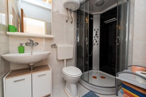 Et moderne badeværelse med hvid vask, toilet og brusekabine med glasvægge.