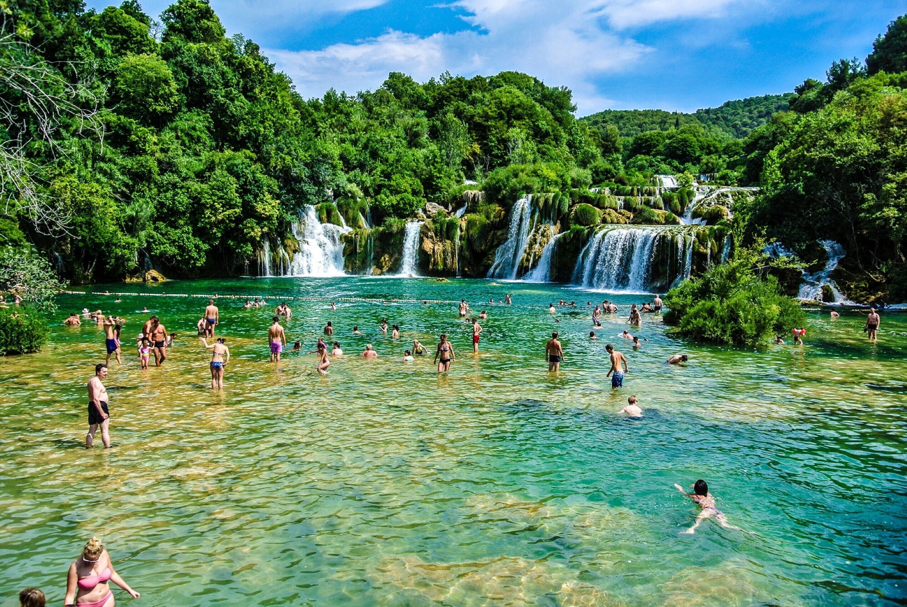 Una piscina natural rodeada de exuberante vegetación y múltiples cascadas.