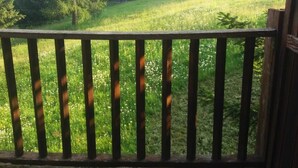 A wooden deck with a view of a building with multiple balconies and a grassy area. - San Sicario Alto Terrazza sui Monti (Italia)