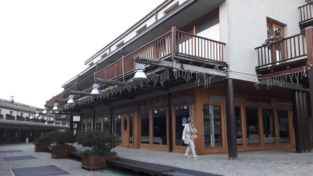 A building with a wooden balcony, outdoor seating, and a sign indicating a restaurant. - San Sicario Alto Terrazza sui Monti (Italia)