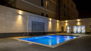Una piscina al aire libre, sillones reclinables de piscina