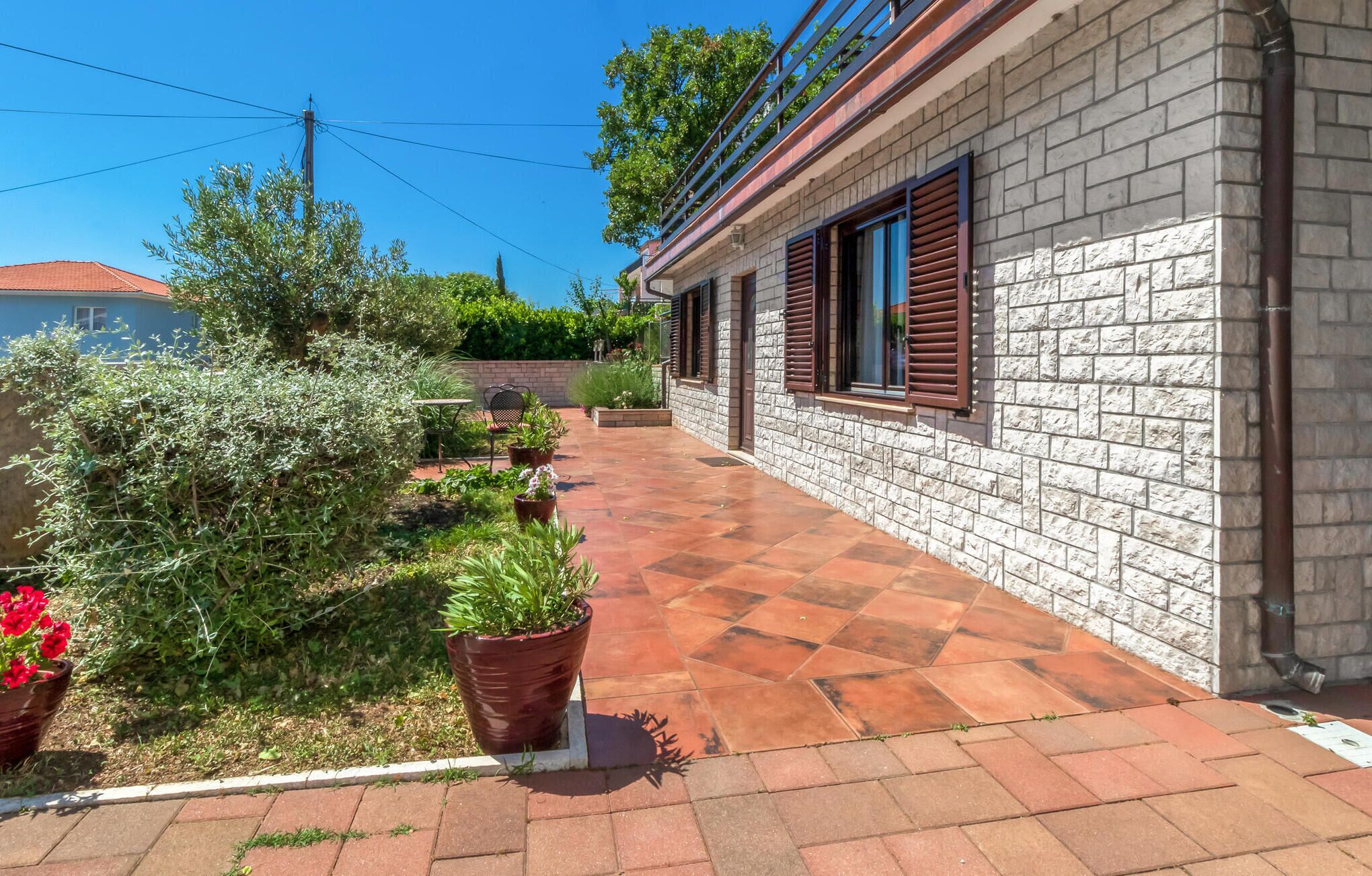 Un chemin pavé bordé de plantes en pot et d’un mur en briques.