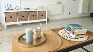 A modern living room with a white cabinet, a television displaying a beach scene, a round mirror, and a tray with candles and books. - Vv Atlantic Garden with pool view, near beach (La Oliva)