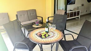 A dining area with a round table, chairs, a sofa, and a TV on the wall. - Vv Atlantic Garden with pool view, near beach (La Oliva)