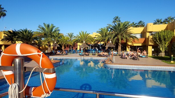 A pool area with lifebuoys, palm trees, and people relaxing. - Vv Atlantic Garden with pool view, near beach (La Oliva)