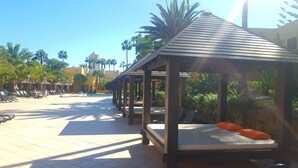 A resort with wooden gazebos, lounge chairs, and a pool area. - Vv Atlantic Garden with pool view, near beach (La Oliva)