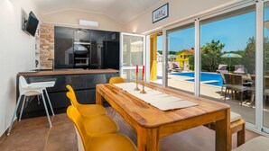 Una cocina moderna con horno empotrado y comedor con mesa de madera y sillas amarillas.