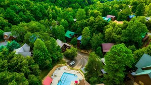 Een resort met meerdere bungalows, omgeven door dicht bos, een zwembad en een weg.