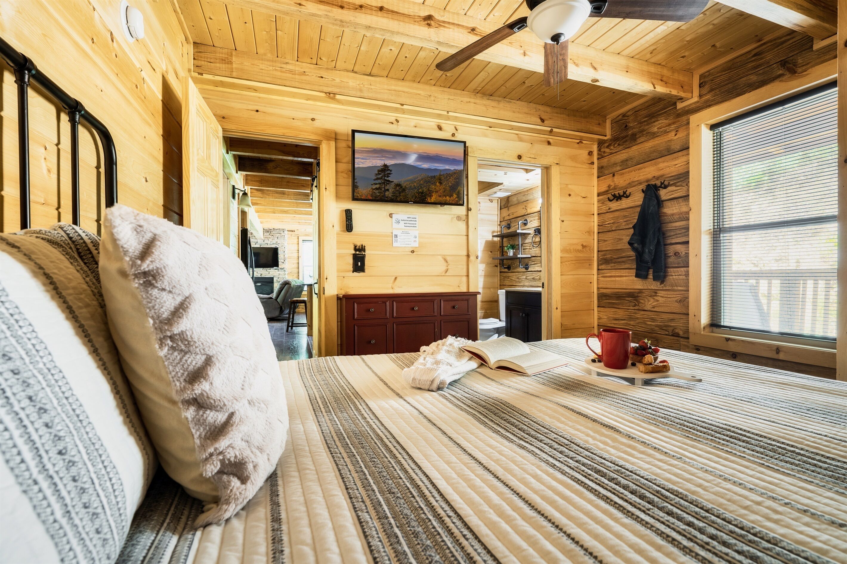 Um quarto de cabana de madeira acolhedor, com uma cama, uma televisão e uma janela com persianas.