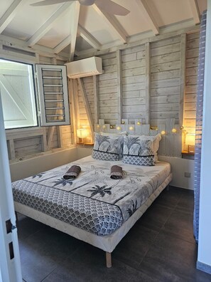 A bedroom with a bed, wooden walls, a window, and a ceiling fan.