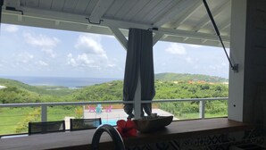 A balcony with a view of a lush landscape and the sea.