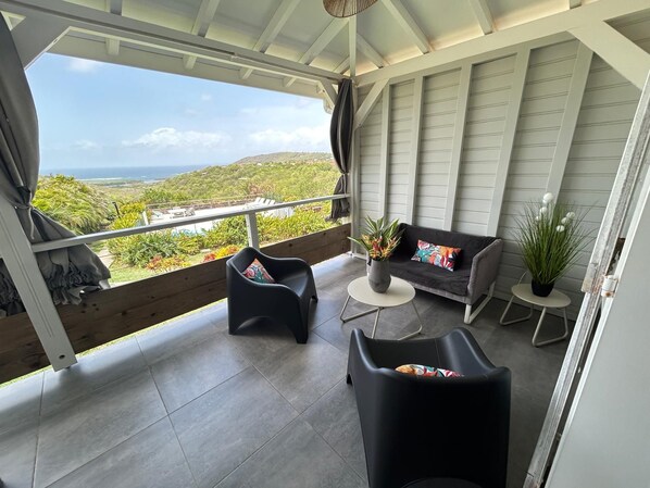 A balcony with a sofa, chairs, and potted plants.