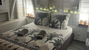 A bedroom with a bed, pillows, and a headboard with lights.