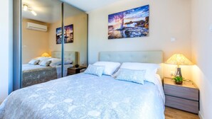 A bedroom with a bed, two bedside tables, a nightstand, a mirror, and wall art. - 3 bedroom gorgeous apartment in Split (Split)
