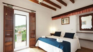 A bedroom with a bed, a window, and a view of greenery outside. - Son Sama (Llucmajor)